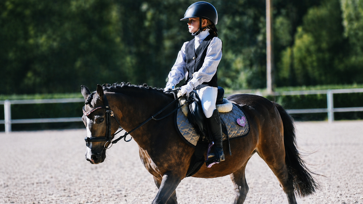 Person riding a horse in an equestrian setting with Balanced Support Reins